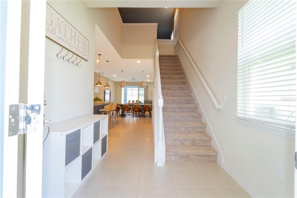 An entryway features a white storage unit, a carpeted staircase, and a view into the kitchen — 3344 LILAC WAY, DAVENPORT, FL