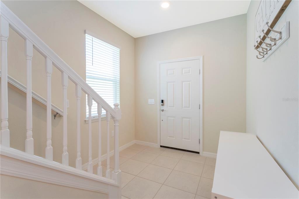An entryway features tile flooring, a white staircase with a railing, and a front door — 3344 LILAC WAY, DAVENPORT, FL