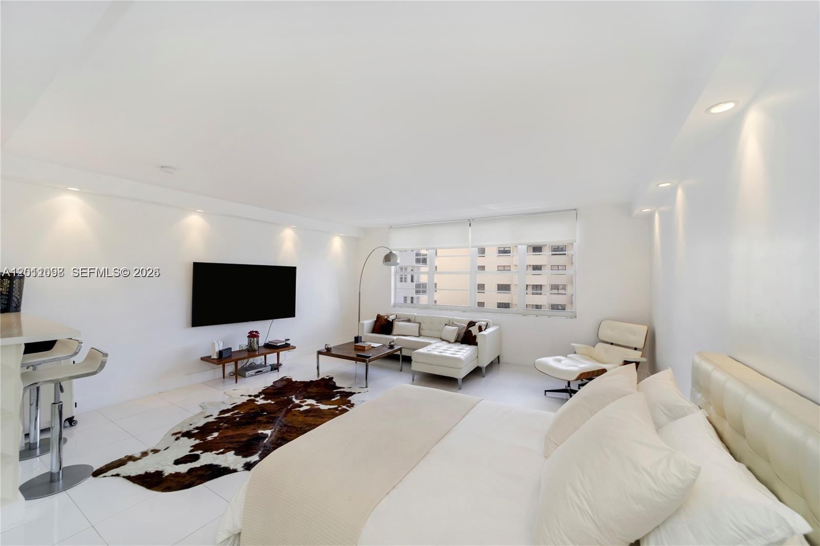 A studio apartment features a bed, white sofa, lounge chair, and a cowhide area rug — 100 Lincoln Rd # 605, Miami Beach FL 33139, MIAMI BEACH, FL