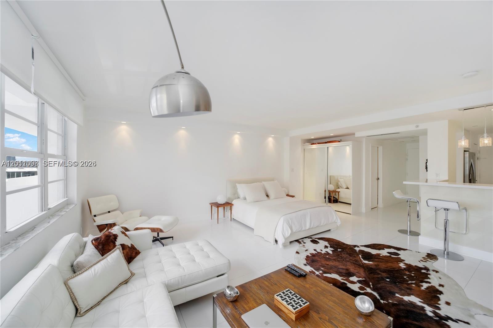 A modern studio apartment features white tile floors, a bed, a sofa, and a kitchen counter — 100 Lincoln Rd # 605, Miami Beach FL 33139, MIAMI BEACH, FL