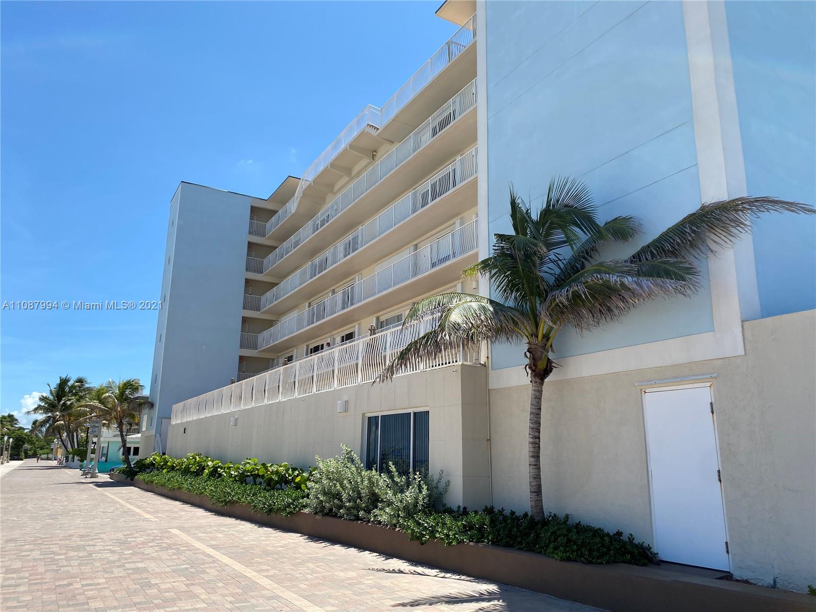 A multi-story light blue building features white balconies and a palm tree in front — 300 Oregon St # 204, Hollywood FL 33019, HOLLYWOOD, FL