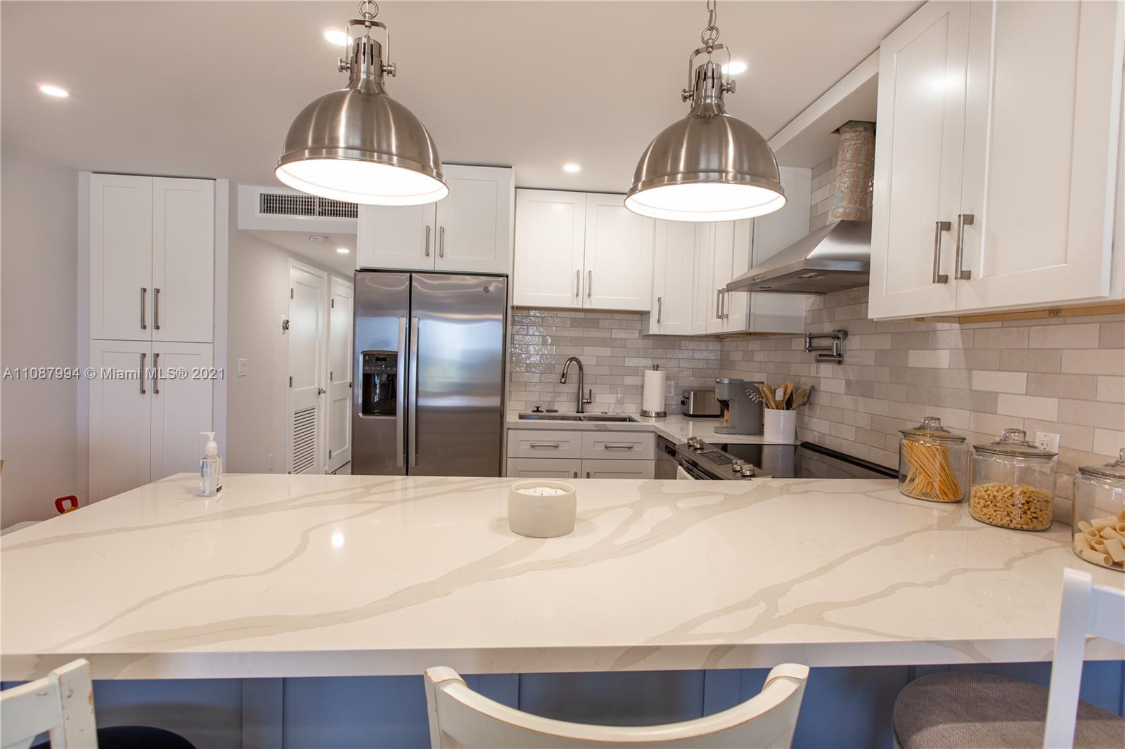 A kitchen features white cabinets, stainless steel appliances, and a large quartz-topped island — 300 Oregon St # 204, Hollywood FL 33019, HOLLYWOOD, FL