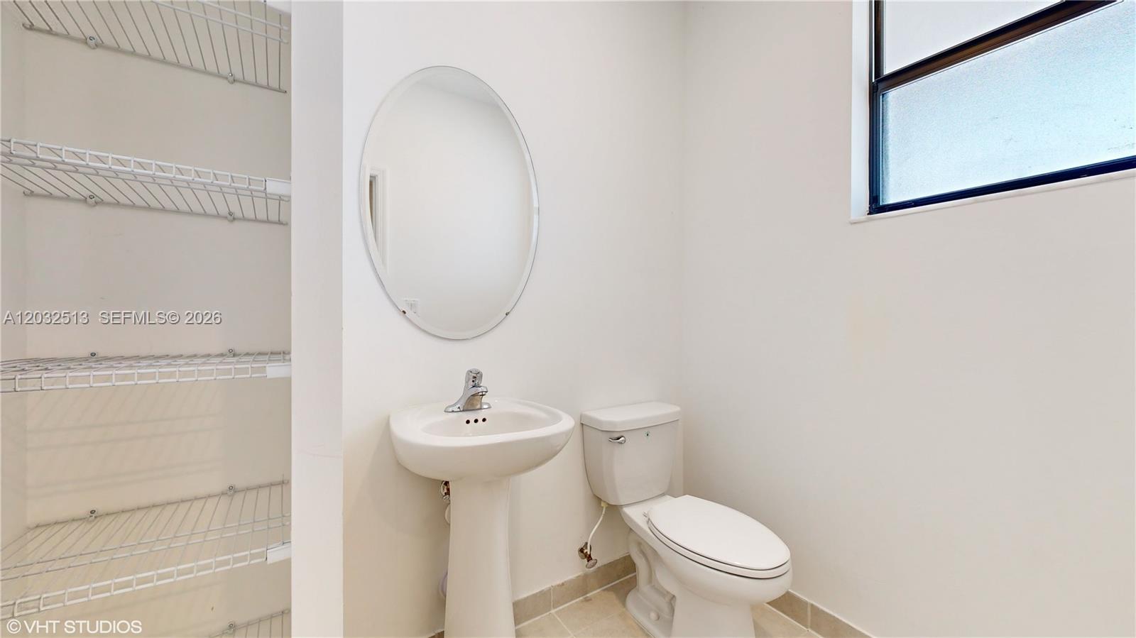 A small bathroom features a pedestal sink, a toilet, and open wire shelving — 10004 SW 231 LN, Miami FL 33190, MIAMI, FL