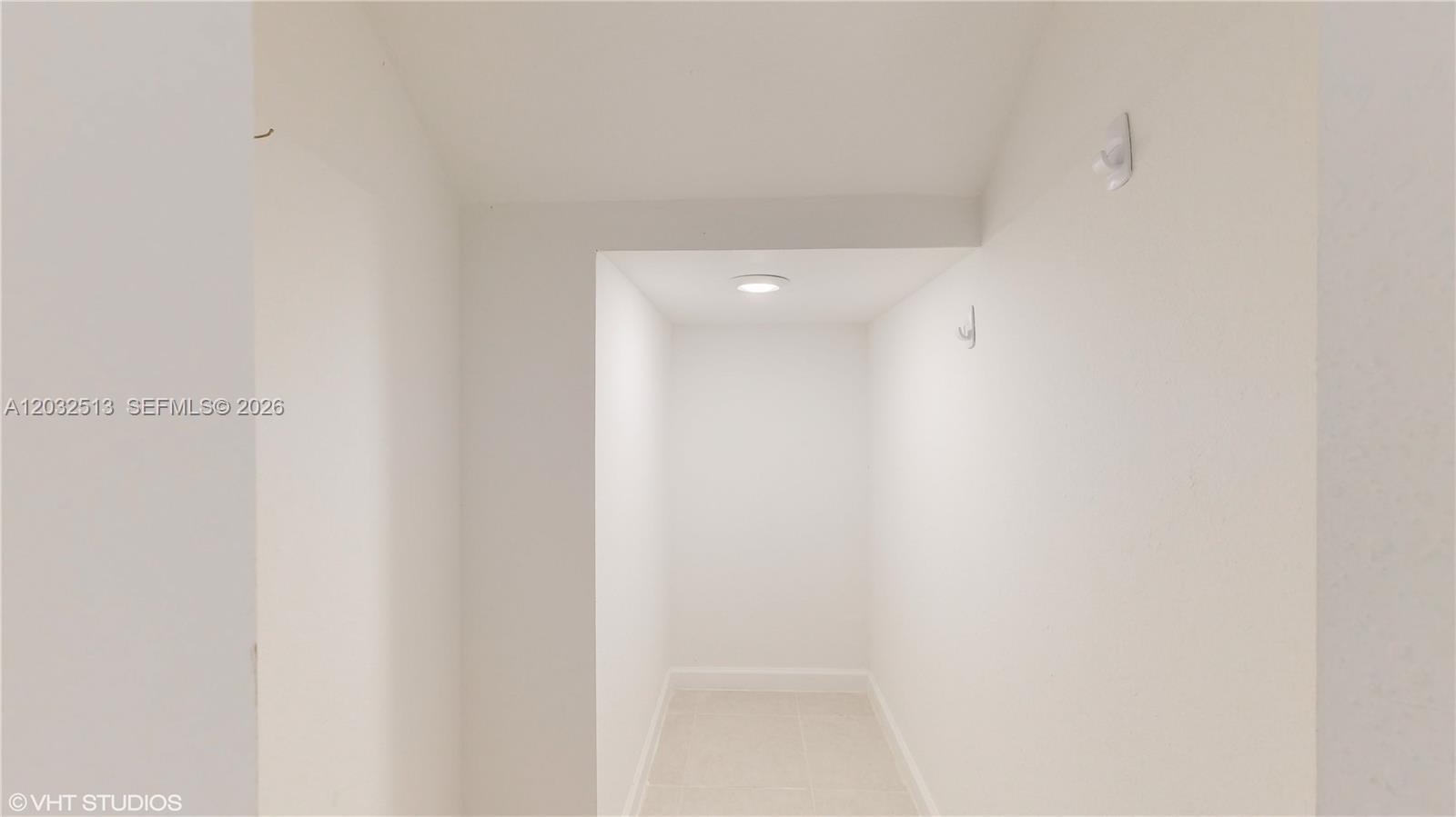 A small, white-walled walk-in closet features a recessed ceiling light and two wall hooks — 10004 SW 231 LN, Miami FL 33190, MIAMI, FL