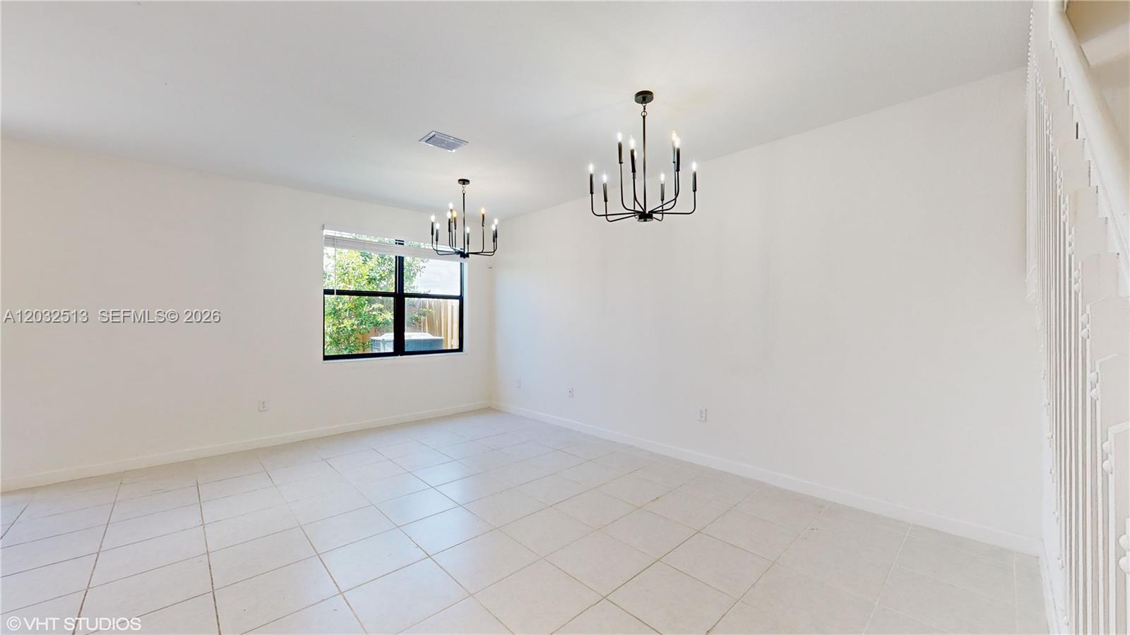An empty room with white walls, tiled floors, and two black metal chandeliers — 10004 SW 231 LN, Miami FL 33190, MIAMI, FL