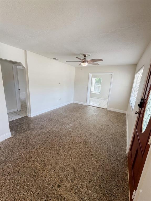 A living room with beige carpet, a ceiling fan, and a doorway leading to another room — 2119 W HENRY AVENUE, TAMPA, FL