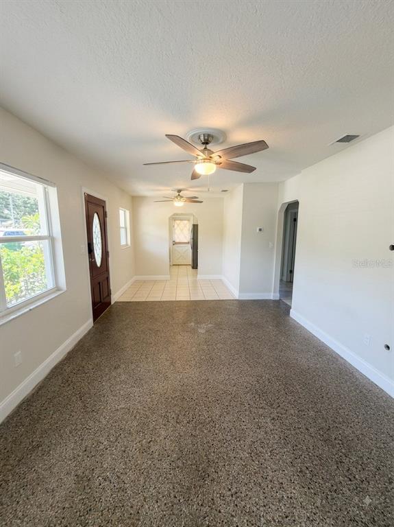 An interior view shows a living area with speckled flooring leading to a tiled dining space — 2119 W HENRY AVENUE, TAMPA, FL