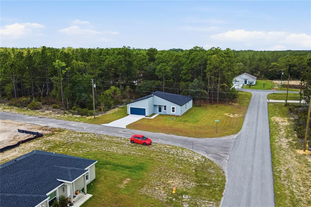 An aerial view shows a modern single-story house with a blue garage and red car — 10708 N CALDERA AVENUE, CITRUS SPRINGS, FL