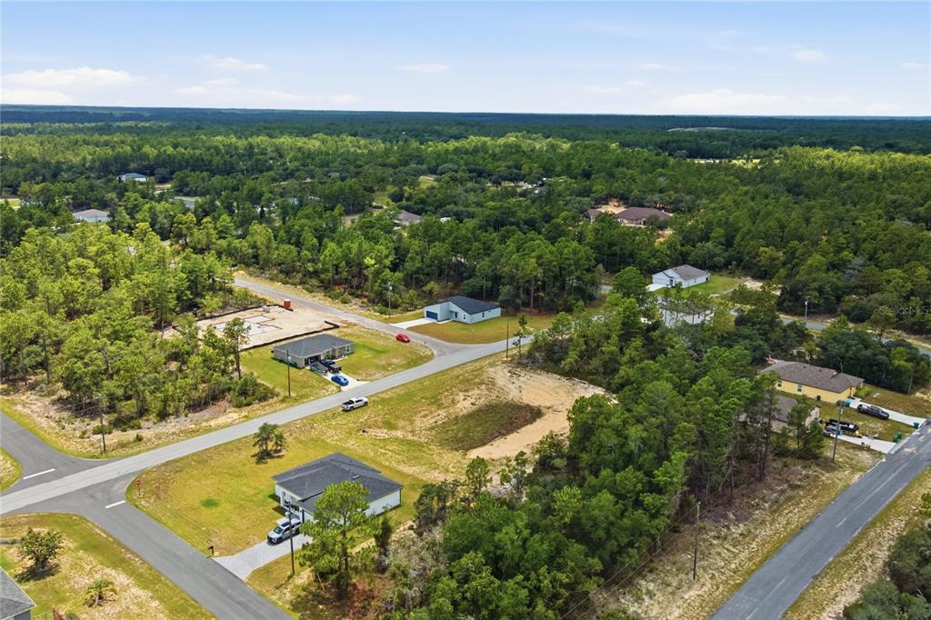 An aerial view shows several houses and a construction site surrounded by dense forest — 10708 N CALDERA AVENUE, CITRUS SPRINGS, FL