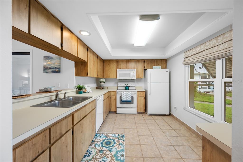 A kitchen with light wood cabinets, white appliances, tile flooring, and a large window — 2060 SHEFFIELD COURT, OLDSMAR, FL
