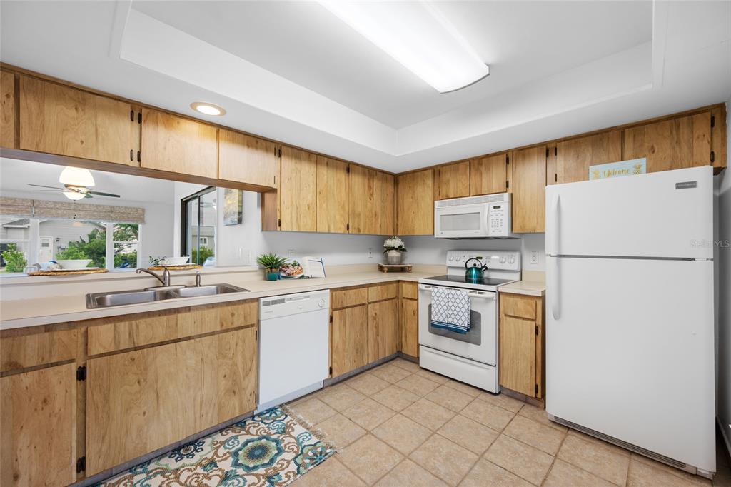 A kitchen with wood cabinets, white appliances, a double sink, and tiled flooring — 2060 SHEFFIELD COURT, OLDSMAR, FL