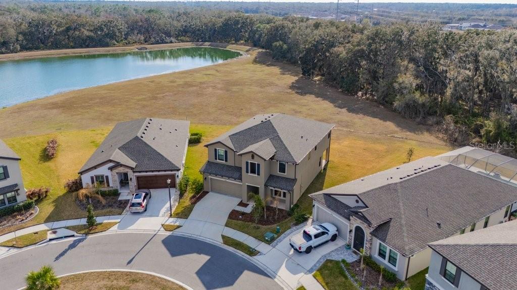 An aerial view shows three suburban houses situated along a cul-de-sac near a pond — 14604 HORSE TROT ROAD, LITHIA, FL
