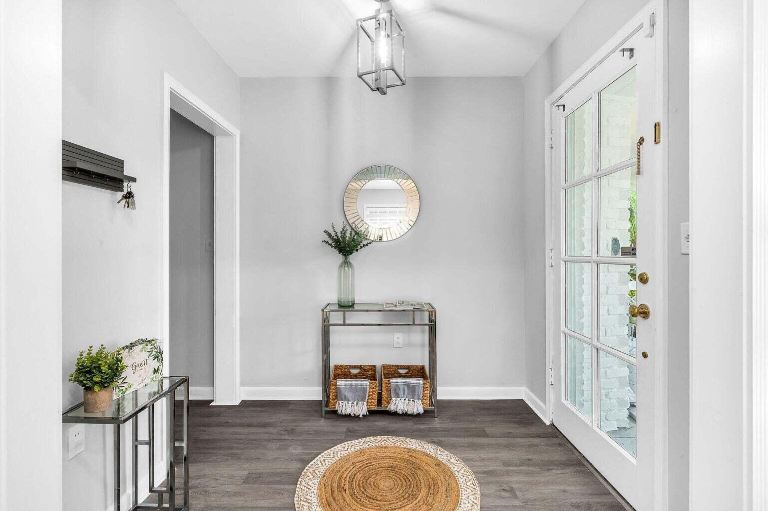 A bright entryway features light gray walls, dark wood-look flooring, a glass console table, and mirror — 127 Miramar Way, West Palm Beach FL 33405, WEST PALM BEACH, FL