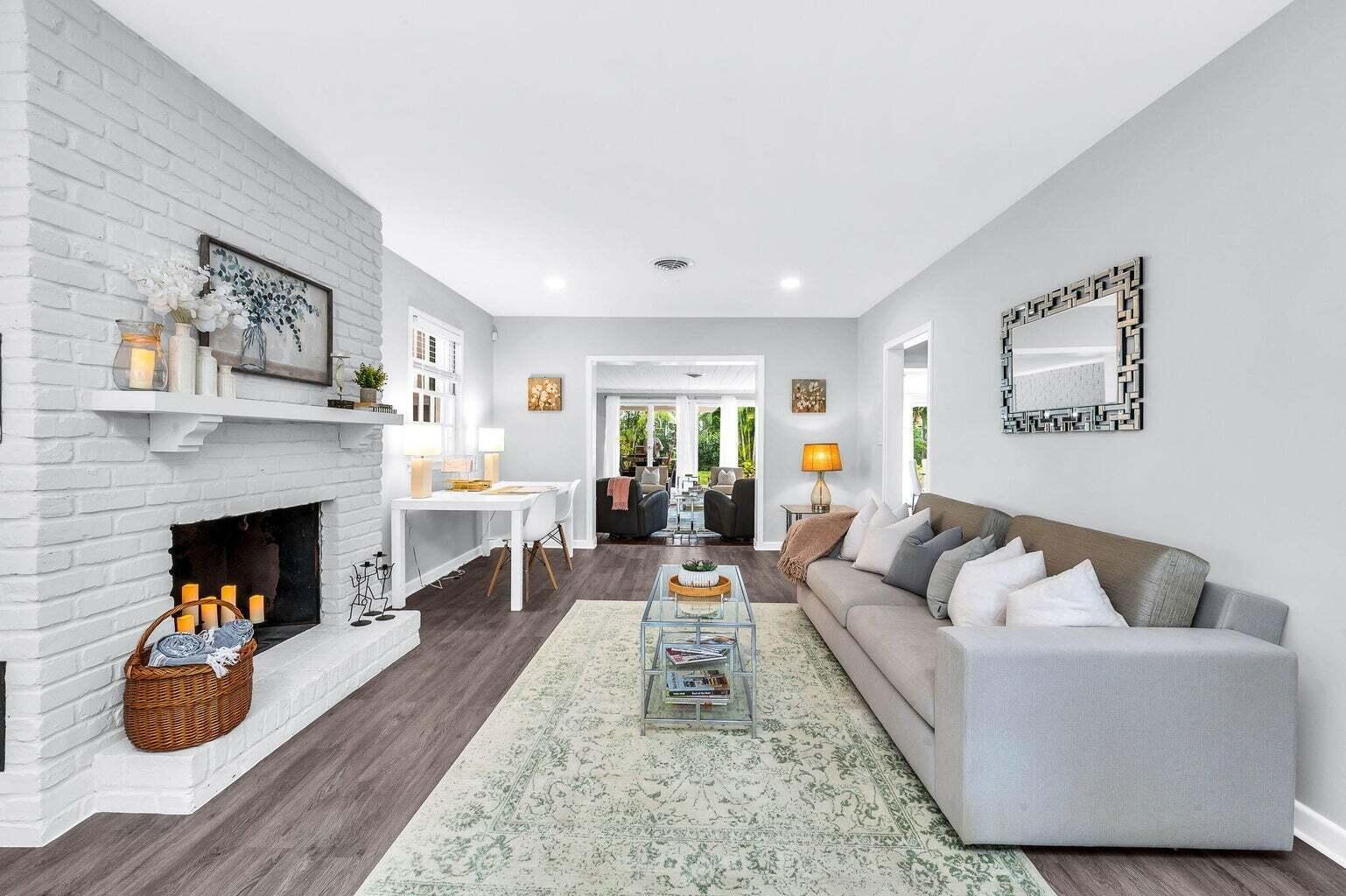A living room with a white brick fireplace, gray sofa, and light-colored area rug — 127 Miramar Way, West Palm Beach FL 33405, WEST PALM BEACH, FL