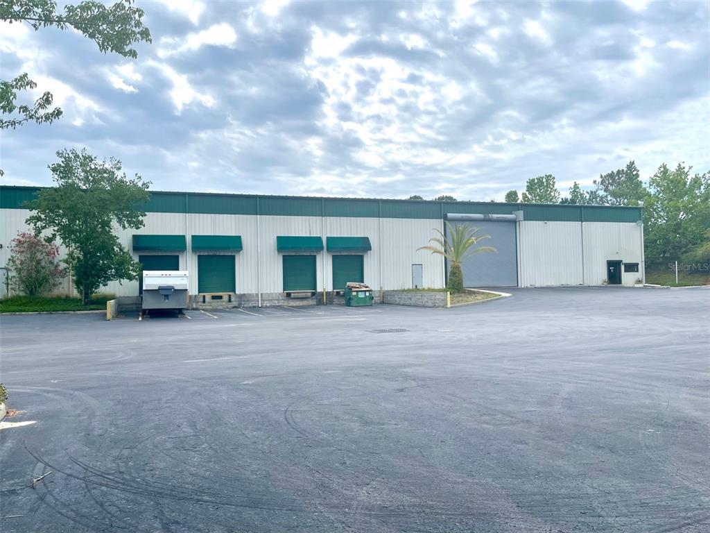 A commercial warehouse building features multiple loading docks and a large roll-up door — 19994 INDEPENDENCE BOULEVARD, GROVELAND, FL