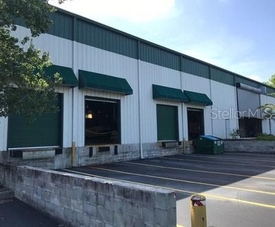 An exterior view of a commercial warehouse building featuring multiple loading dock bays and awnings — 19994 INDEPENDENCE BOULEVARD, GROVELAND, FL