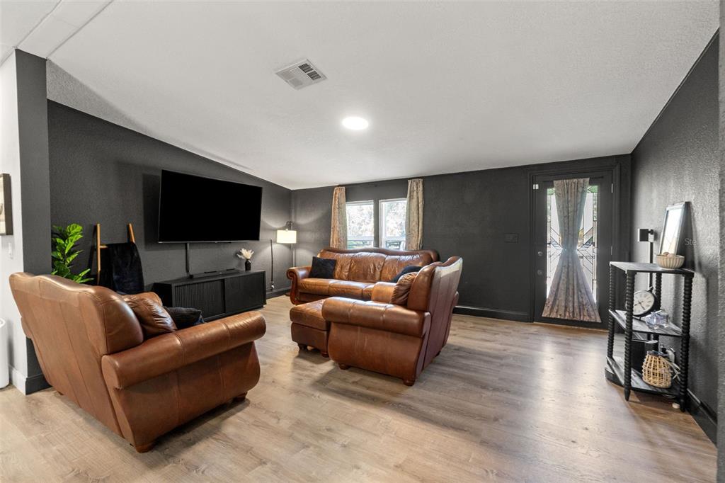 A living room features dark gray walls, leather furniture, and light wood-look flooring — 6886 W EDGEWOOD LANE, HOMOSASSA, FL