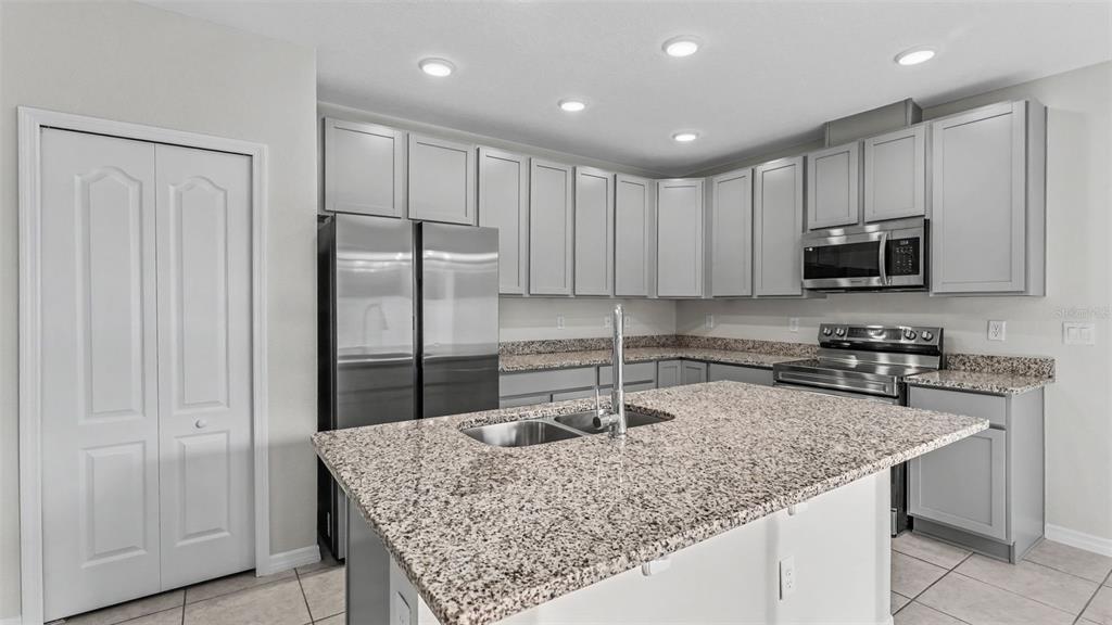 A kitchen features gray cabinets, granite countertops, stainless steel appliances, and a central island — 4925 JACKSON STREET, WINTER HAVEN, FL