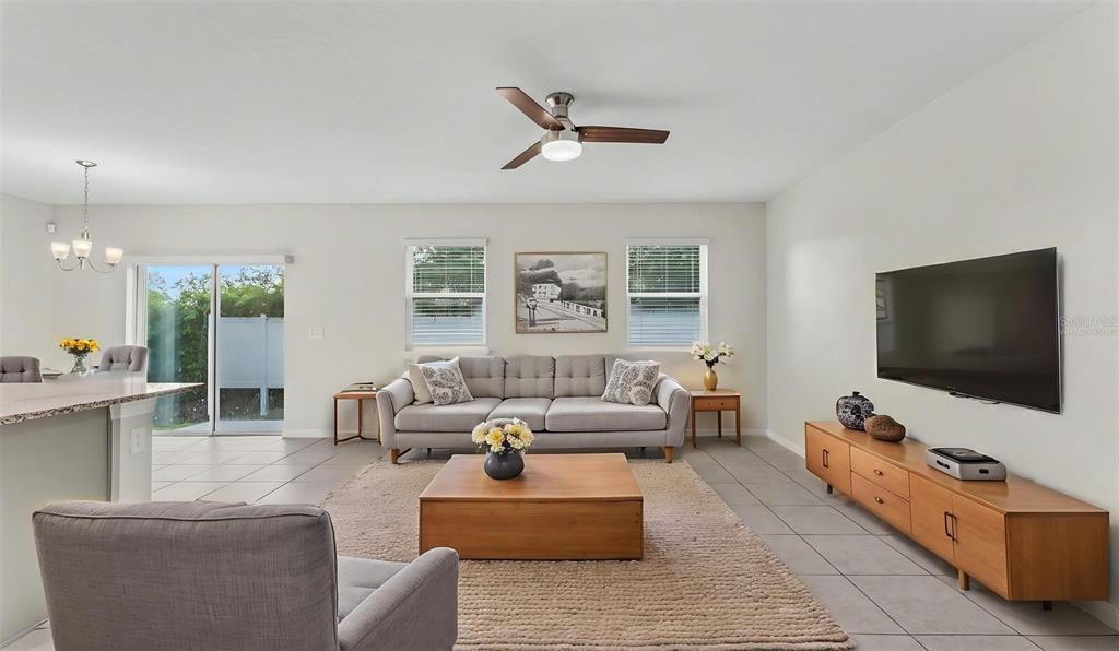 A living room features a gray sofa, wooden coffee table, media console, and tile flooring — 4925 JACKSON STREET, WINTER HAVEN, FL