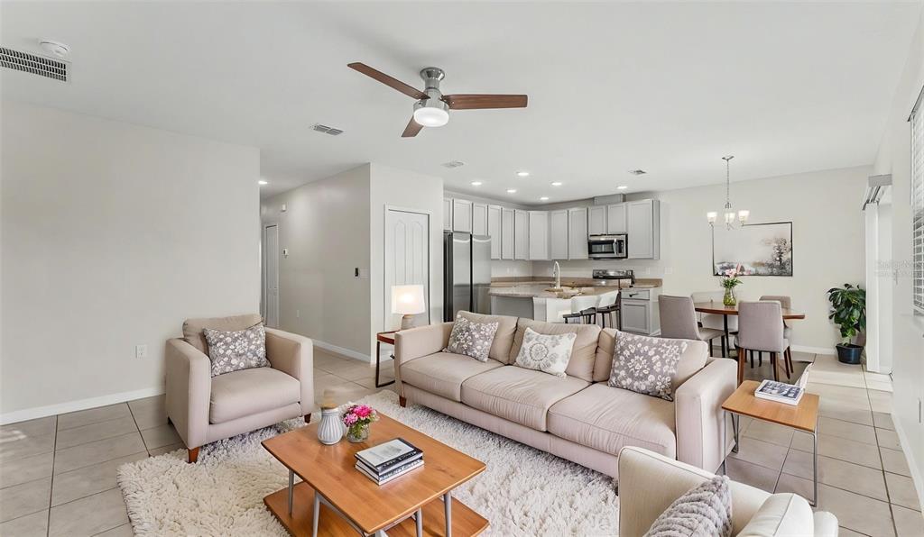An open-concept living room and kitchen featuring light-colored furniture, tile floors, and a ceiling fan — 4925 JACKSON STREET, WINTER HAVEN, FL
