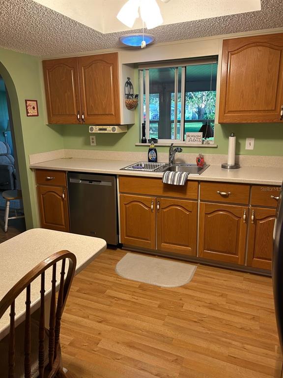 A kitchen features wood cabinets, a stainless steel dishwasher, a sink, and light-colored countertops — 10397 SE 176TH STREET, SUMMERFIELD, FL