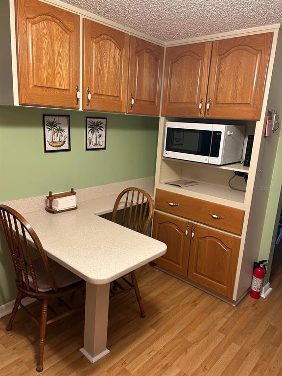 A kitchen nook features oak cabinets, a microwave, a built-in table, and two wooden chairs — 10397 SE 176TH STREET, SUMMERFIELD, FL
