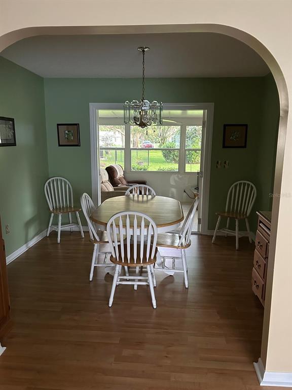 A dining room with green walls, a wooden table, white chairs, and a chandelier — 10397 SE 176TH STREET, SUMMERFIELD, FL