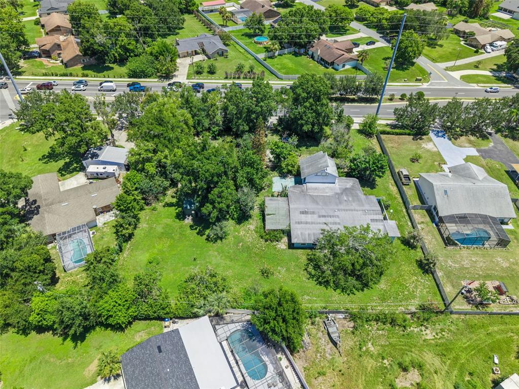 An aerial view shows several residential properties with swimming pools and trees near a road — 1730 NEPTUNE ROAD, KISSIMMEE, FL