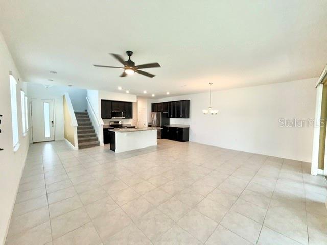 An open-concept kitchen with dark cabinets and a center island overlooks a tiled living area — 2337 SHADOWLAND LOOP, WINTER PARK, FL