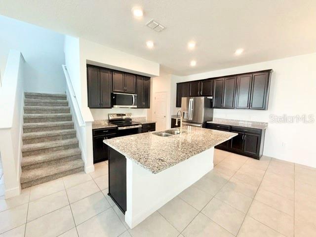 A kitchen features dark cabinets, granite countertops, a central island, and an adjacent carpeted staircase — 2337 SHADOWLAND LOOP, WINTER PARK, FL