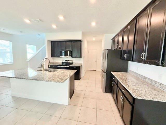 A kitchen features dark cabinets, granite countertops, a large island, and stainless steel appliances — 2337 SHADOWLAND LOOP, WINTER PARK, FL