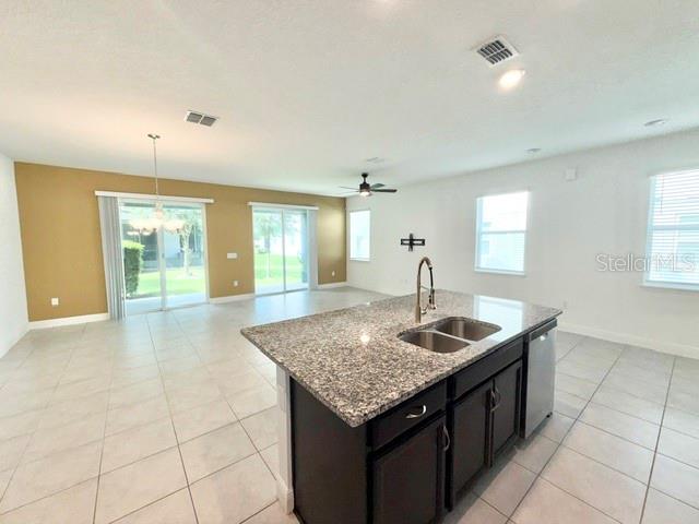 A kitchen island with granite countertops sits in an open-concept room with tile flooring — 2337 SHADOWLAND LOOP, WINTER PARK, FL