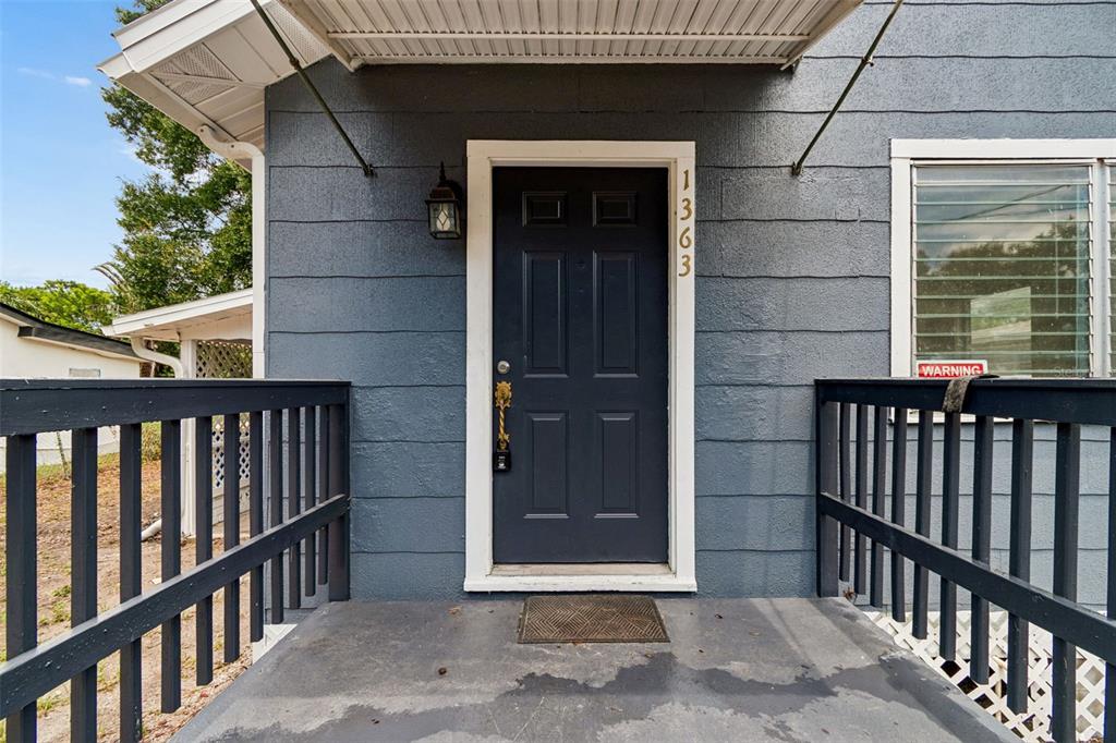 A dark blue front door with a gold handle sits on a covered porch — 1363 TIOGA AVENUE, CLEARWATER, FL