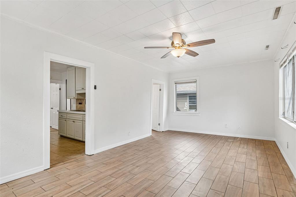 A bright living room features light-colored wood-look tile flooring, white walls, and a ceiling fan — 1363 TIOGA AVENUE, CLEARWATER, FL