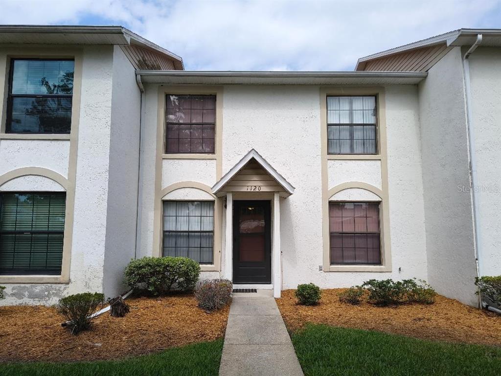 A two-story residential building with a stucco exterior, a central entrance, and a concrete walkway — 1120 N ILLINOIS AVENUE, ST CLOUD, FL