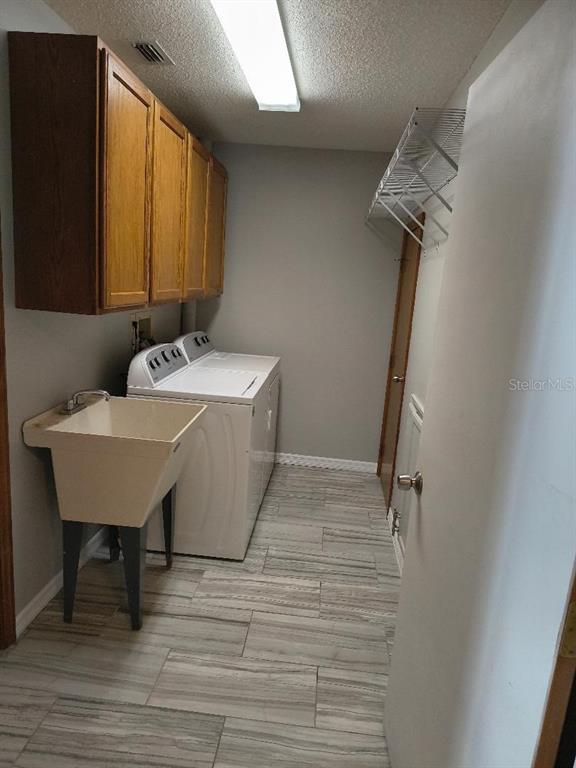 A laundry room features a utility sink, white washer and dryer, and wood cabinetry — 1120 N ILLINOIS AVENUE, ST CLOUD, FL
