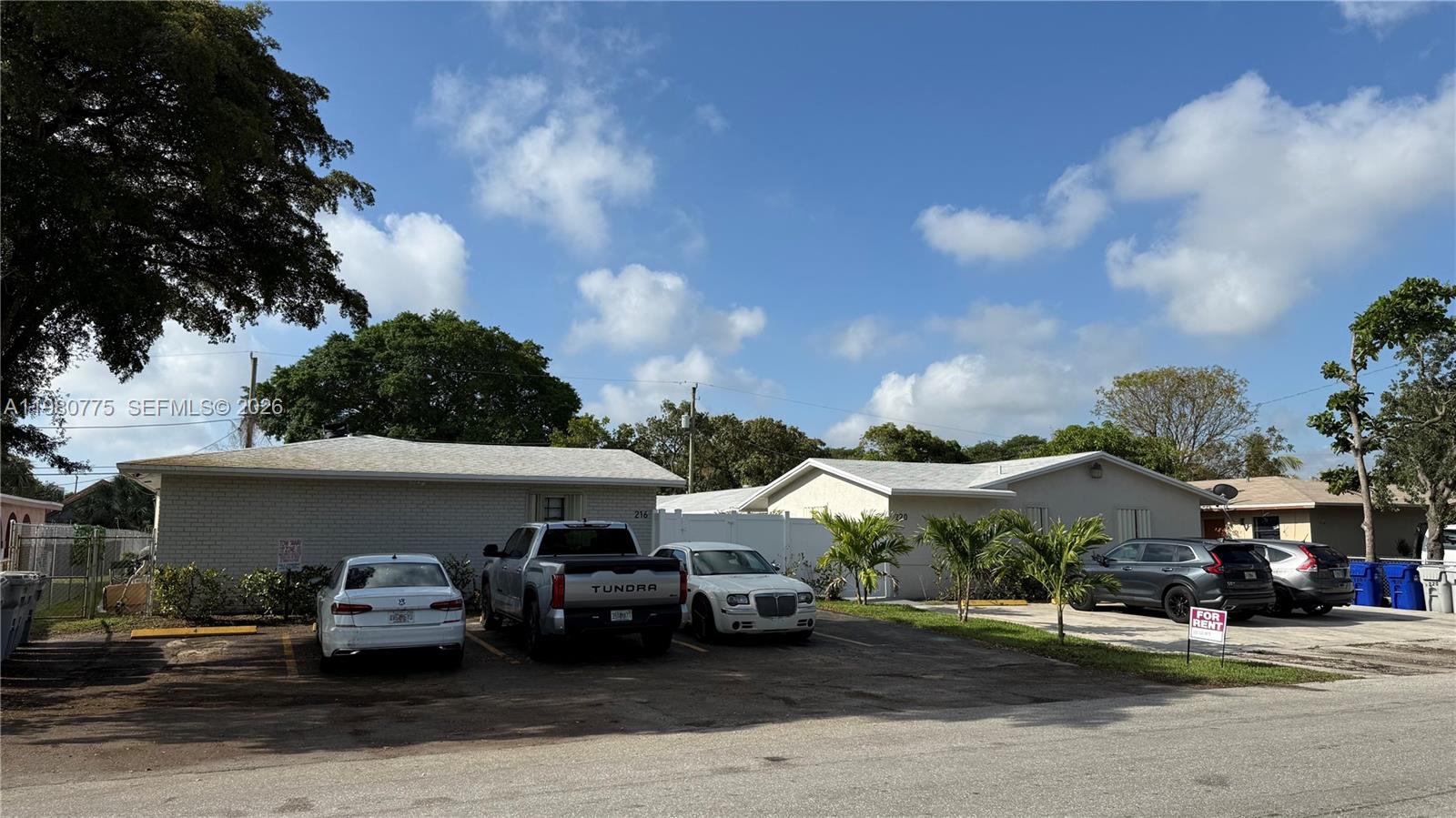 A parking lot sits in front of two single-story residential buildings under a blue sky — 220 NW 12th St, Pompano Beach FL 33060, POMPANO BEACH, FL