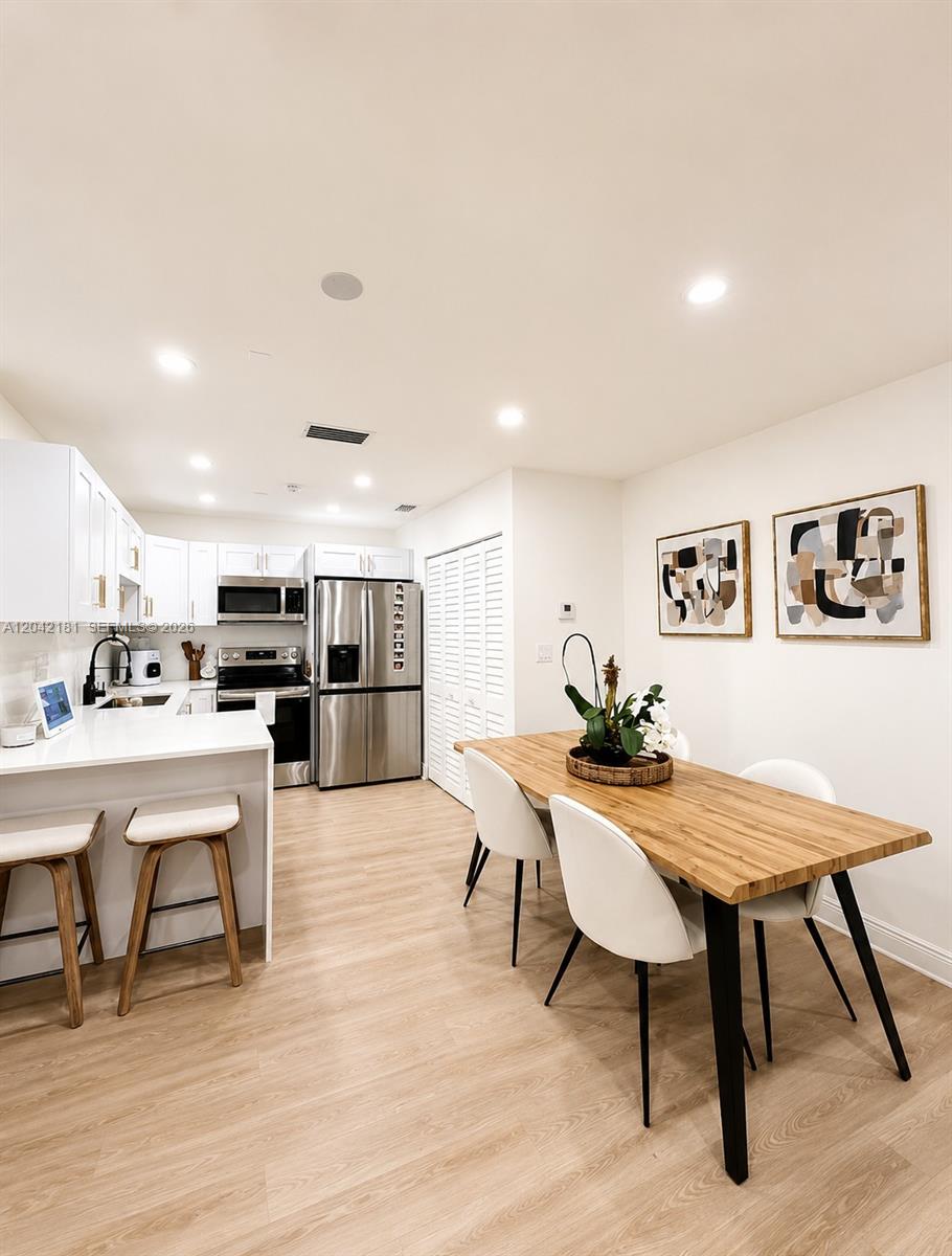 A kitchen with white cabinets and stainless steel appliances opens to a dining area — 13251 SW 17th Ln # 5, Miami FL 33175, MIAMI, FL