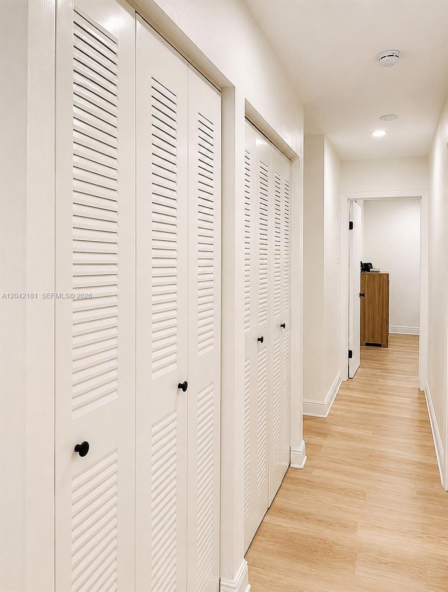 A hallway features light wood-look flooring and two sets of white louvered closet doors — 13251 SW 17th Ln # 5, Miami FL 33175, MIAMI, FL