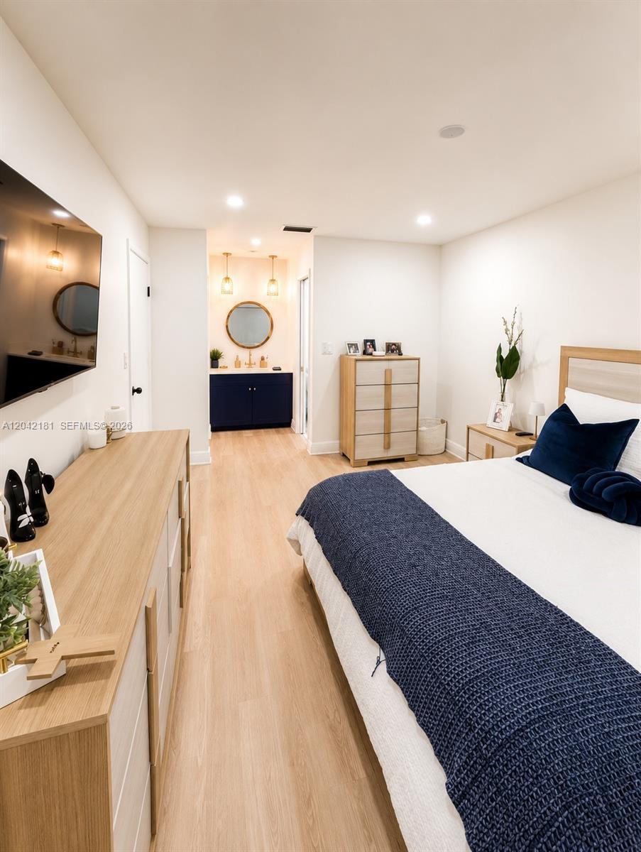 A bedroom features light wood flooring, a navy blue vanity area, and a bed with blue bedding — 13251 SW 17th Ln # 5, Miami FL 33175, MIAMI, FL