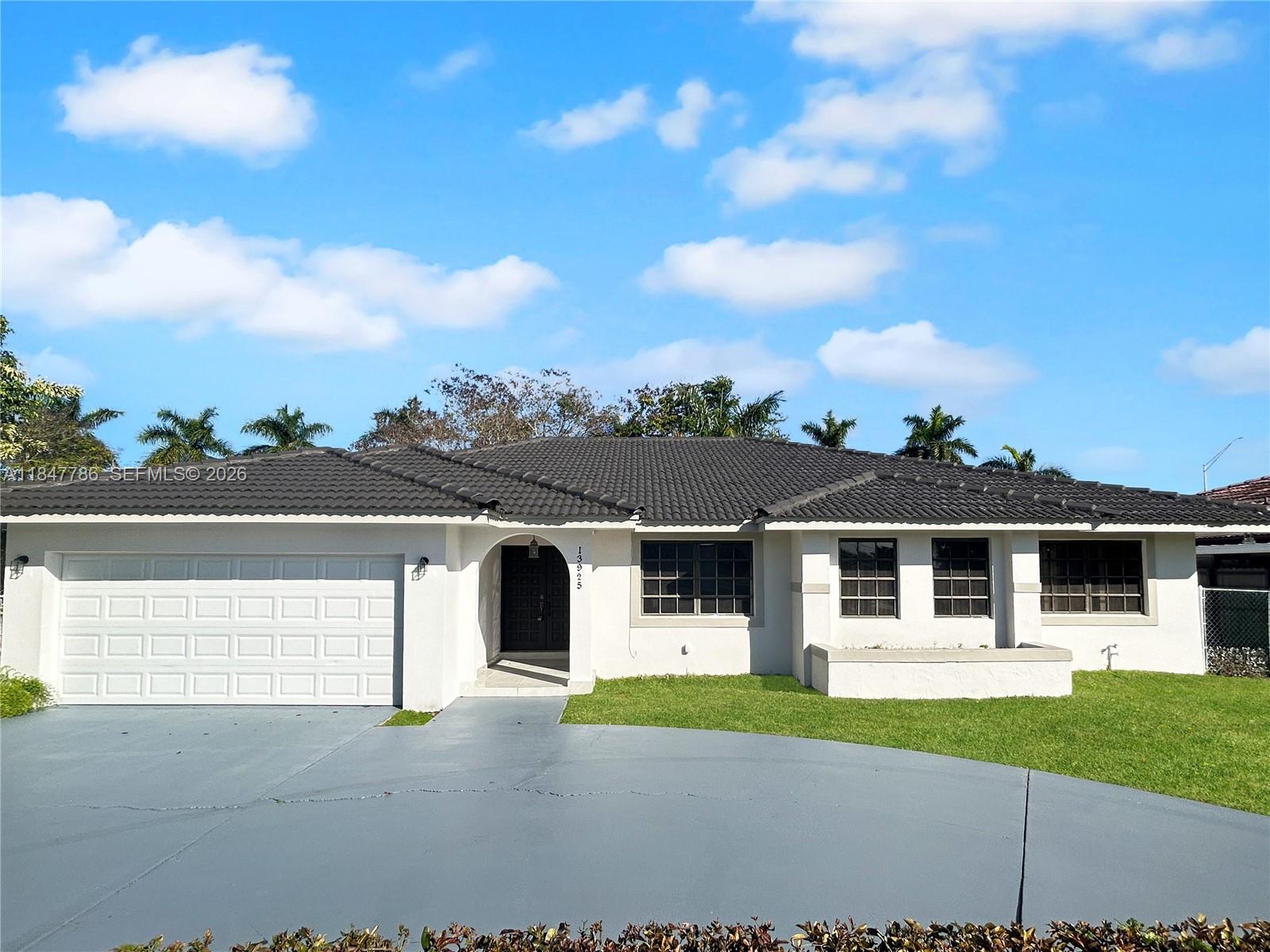 A single-story house with a white stucco exterior, dark tile roof, and a gray driveway — 13925 SW 26th Ter, Miami FL 33175, MIAMI, FL