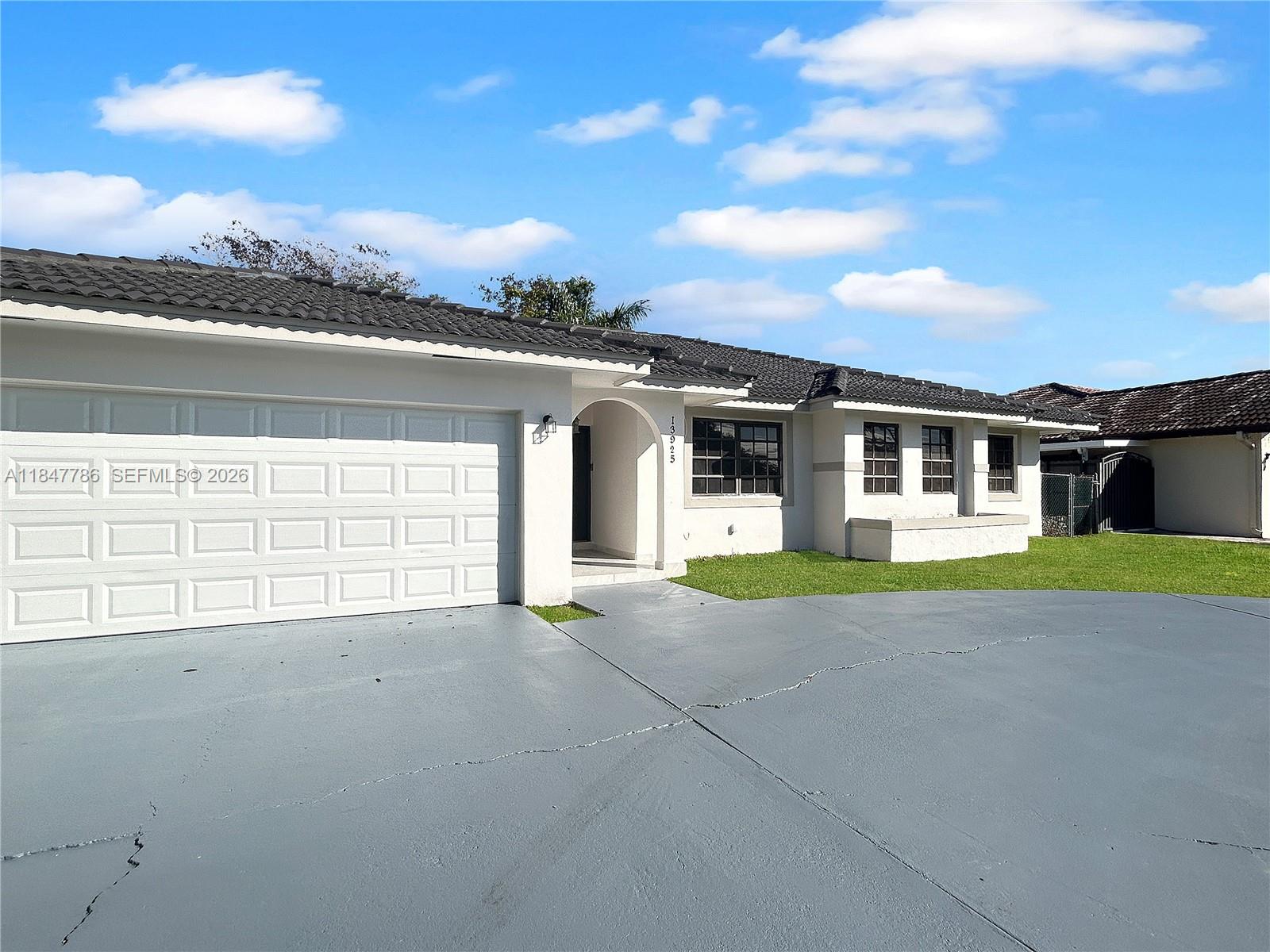 A single-story house with a white stucco exterior, a gray tiled roof, and a driveway — 13925 SW 26th Ter, Miami FL 33175, MIAMI, FL