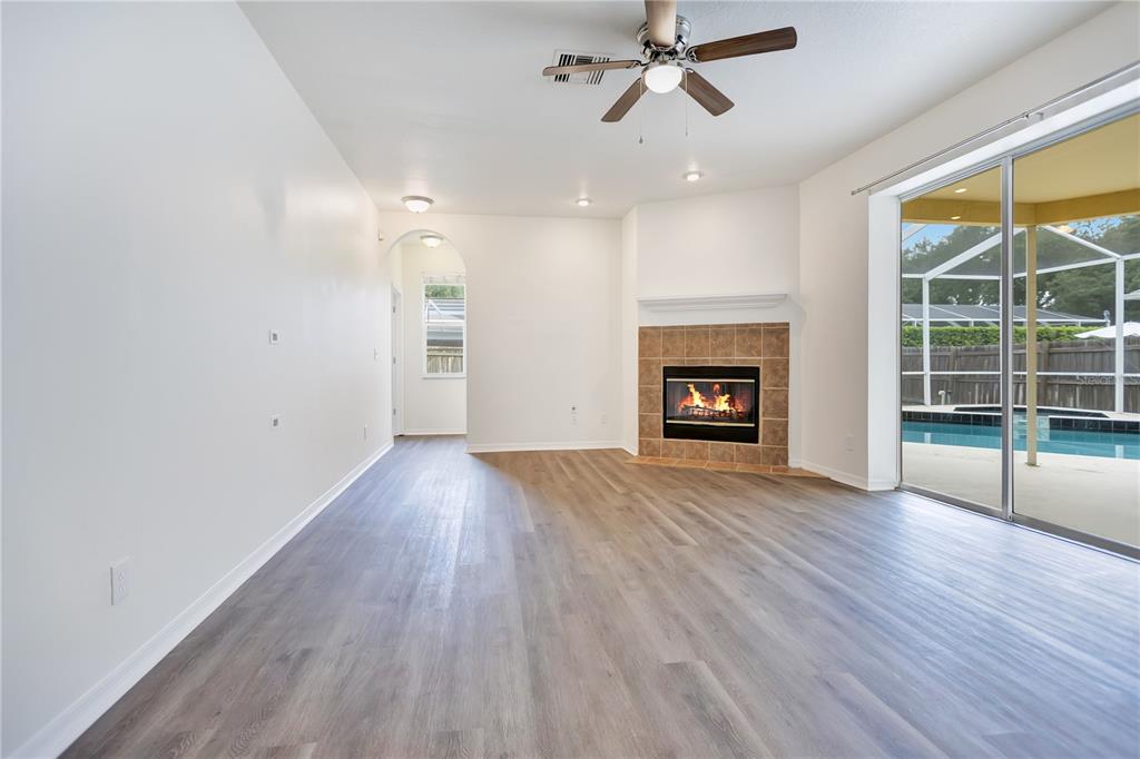 A living room features wood-look flooring, a corner fireplace, a ceiling fan, and sliding glass doors — 9303 HERITAGE OAK COURT, TAMPA, FL