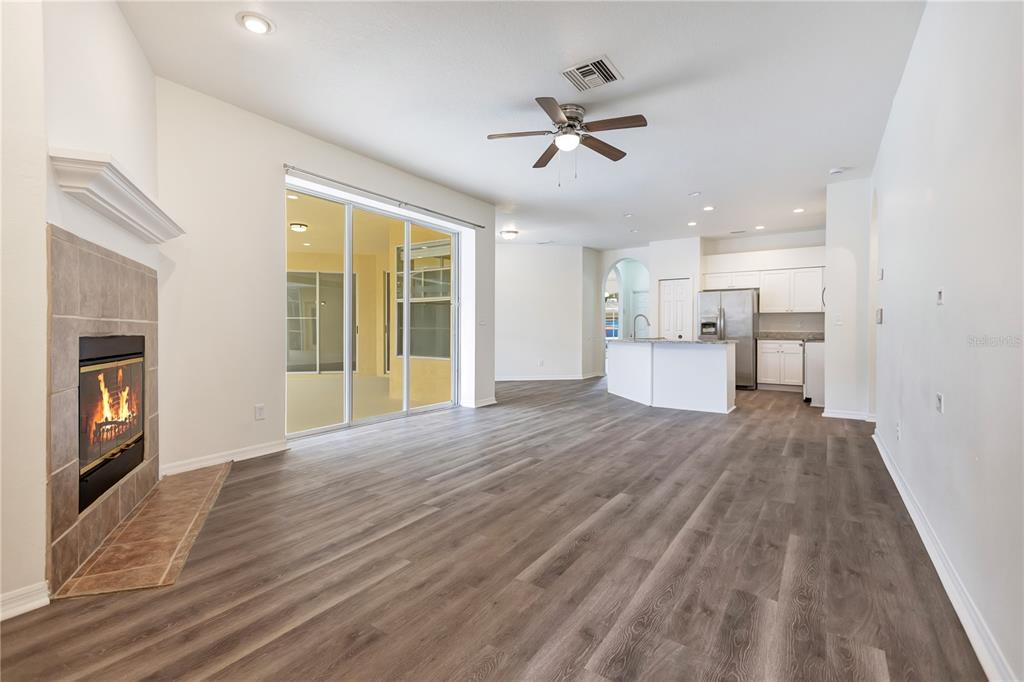 An open-concept living area features a fireplace, sliding glass doors, and a kitchen with white cabinets — 9303 HERITAGE OAK COURT, TAMPA, FL
