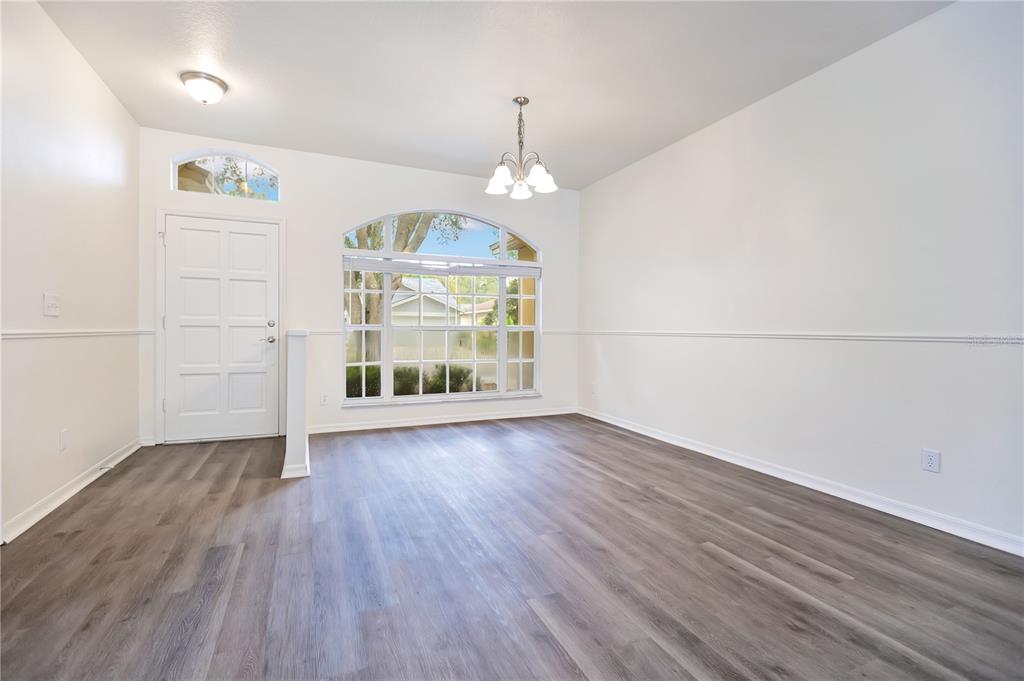 An empty room with white walls, chair rail molding, and gray wood-look flooring — 9303 HERITAGE OAK COURT, TAMPA, FL