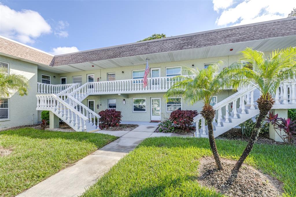 A two-story apartment building with a white exterior, outdoor staircases, and a grassy lawn — 1250 S PINELLAS AVENUE UNIT 711, TARPON SPRINGS, FL