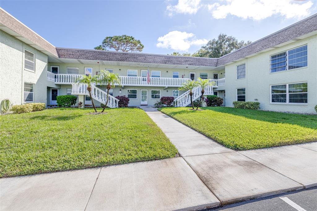 A two-story apartment building features a central courtyard with a walkway and two staircases — 1250 S PINELLAS AVENUE UNIT 711, TARPON SPRINGS, FL