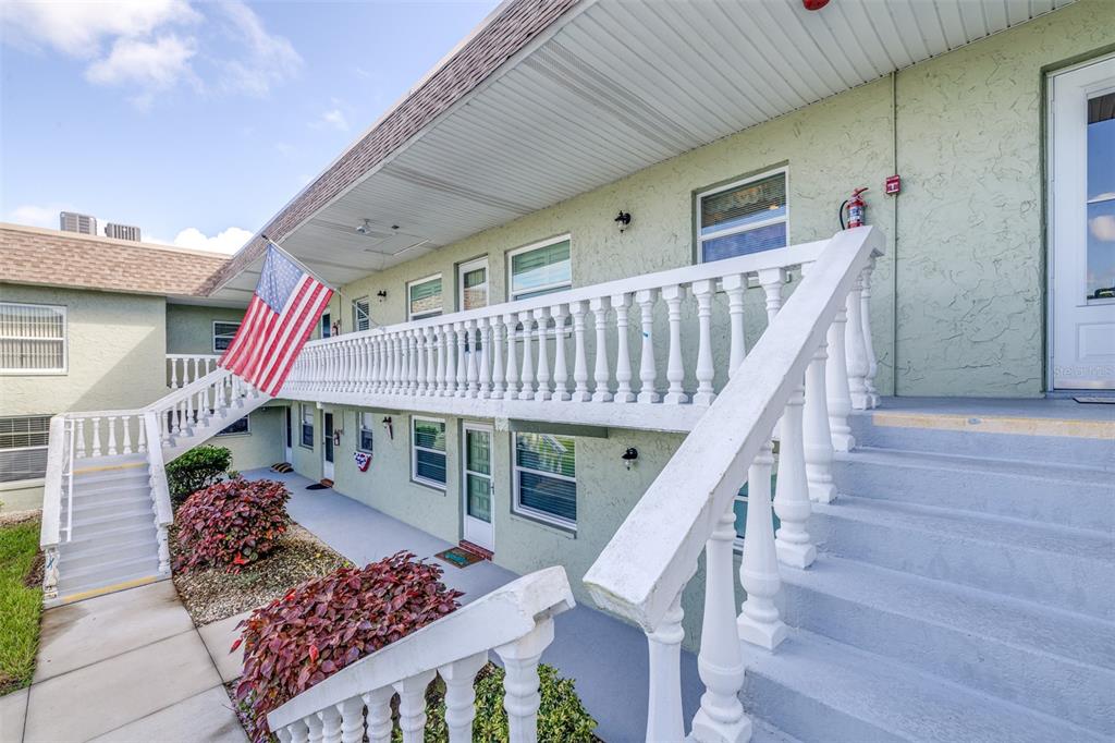 An exterior view of a two-story apartment building with white railings and stairs — 1250 S PINELLAS AVENUE UNIT 711, TARPON SPRINGS, FL