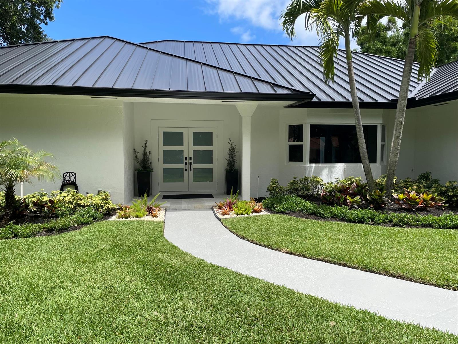 A white house with a dark metal roof and a double front door entrance — 18457 SE Heritage Oaks Lane, Jupiter FL 33469, JUPITER, FL