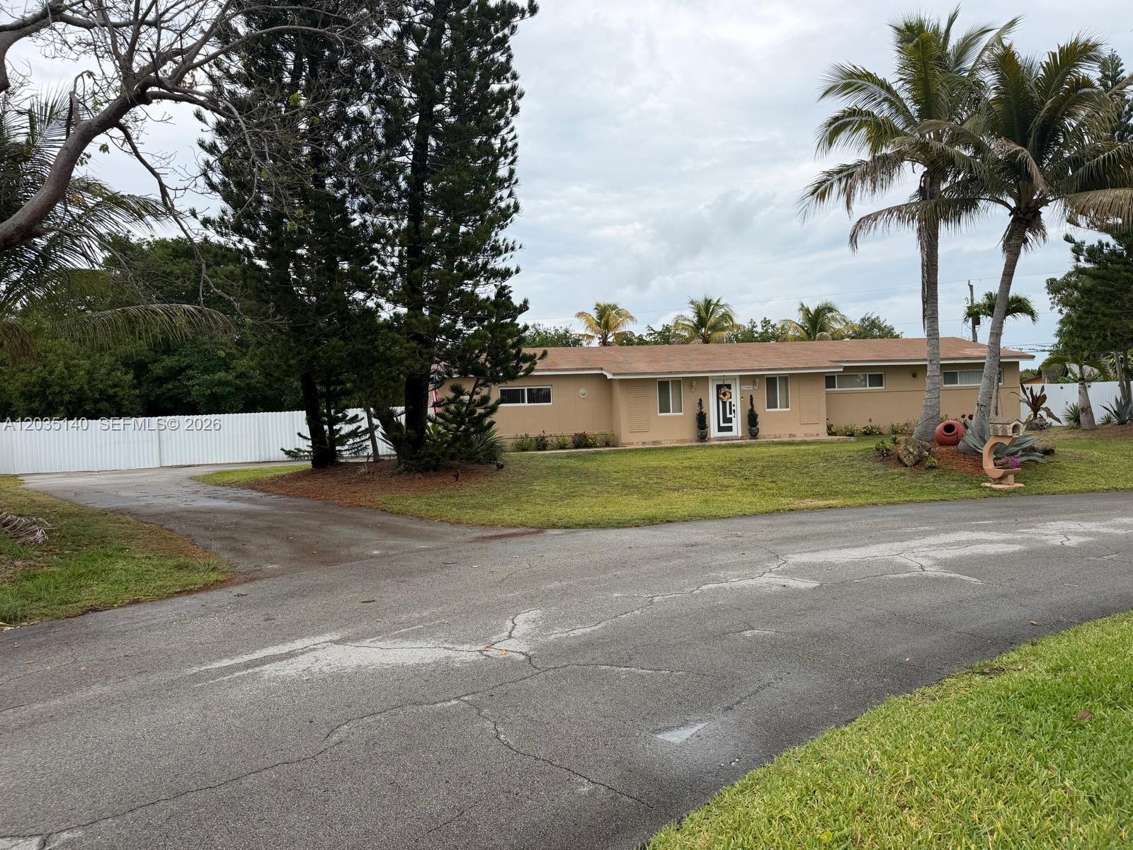 A single-story tan house with a brown roof sits behind a paved driveway and lawn — 17405 SW 109th Ct, Miami FL 33157, MIAMI, FL